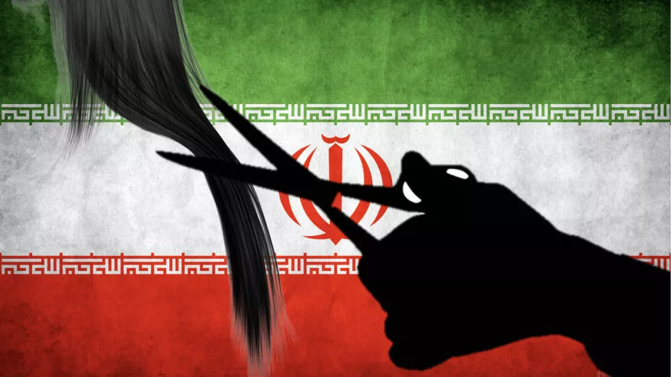 A silhoutte of a hand holding a pair of scissors and cutting a lock of hair in front of the Iranian flag
