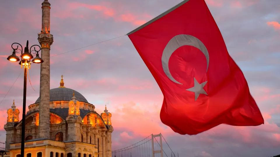 A photo of a Turkish flag and a mosque.
