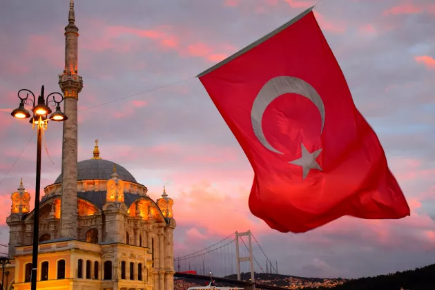 A photo of a Turkish flag and a mosque.